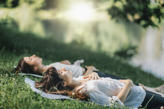 deux personnes qui méditent allongées dans l'herbe