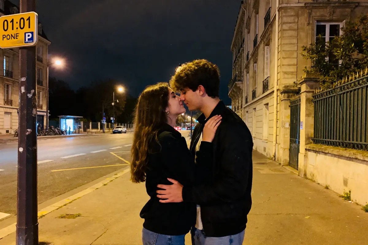Un couple s'embrasse sous un panneau indiquant 01h01, signification amoureuse mystérieuse.