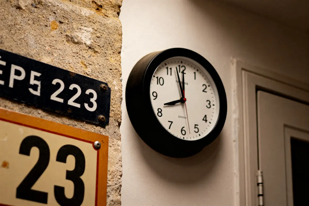 Horloge murale indiquant 23:23 heure miroir près de panneaux numérotés sur un mur