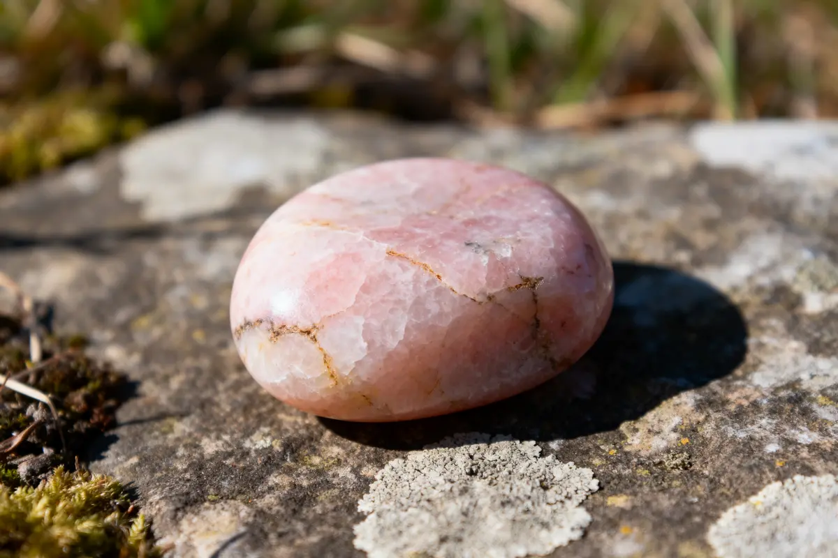 Pierre de jaspe rose lisse posée sur un rocher en extérieur ensoleillé